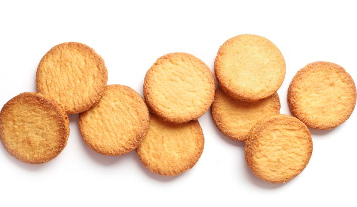 Fotografia vista de cima de biscoitinhos amanteigados sobre uma mesa branca.