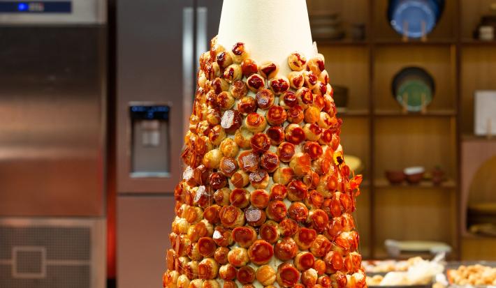 Fotografia em tons de caramelo com uma torre de choux com creme de confeiteiro com toque de laranja.