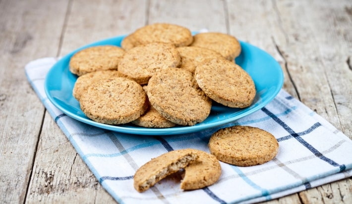 Em cima de uma mesa, prato redondo com porção de biscoitos redondos e crocantes.
