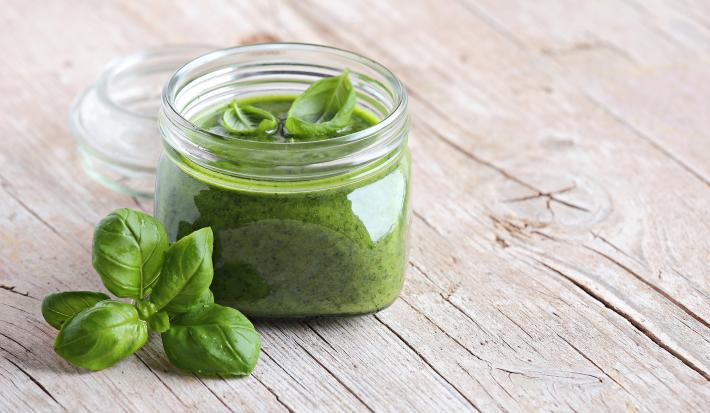 fotografia em tons de bege e verde de uma bancada bege vista de frente. Contem um potinho com creme verde dentro.
