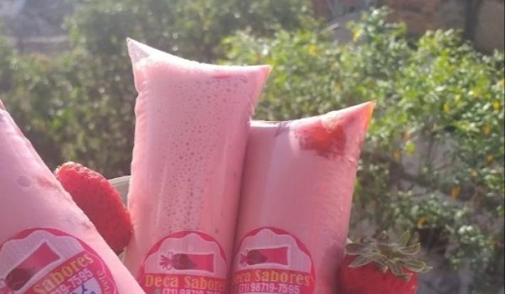 Fotografia de geladinhos gourmet de morango, com alguns morangos juntos.