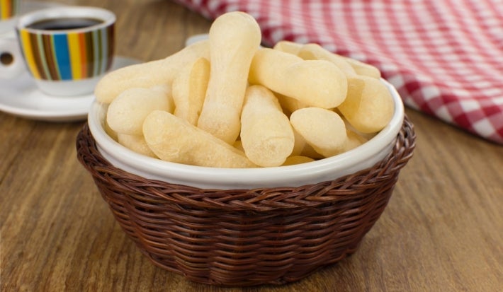 Em cima de uma mesa, tigela com biscoitos de polvilho crocantes e dourados.