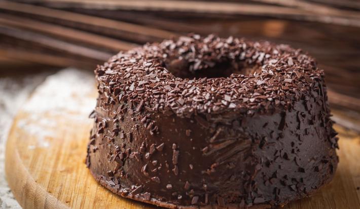 Foto da receita de Bolo de Chocolate. Observa-se um bolo com furo central e cobertura de brigadeiro.