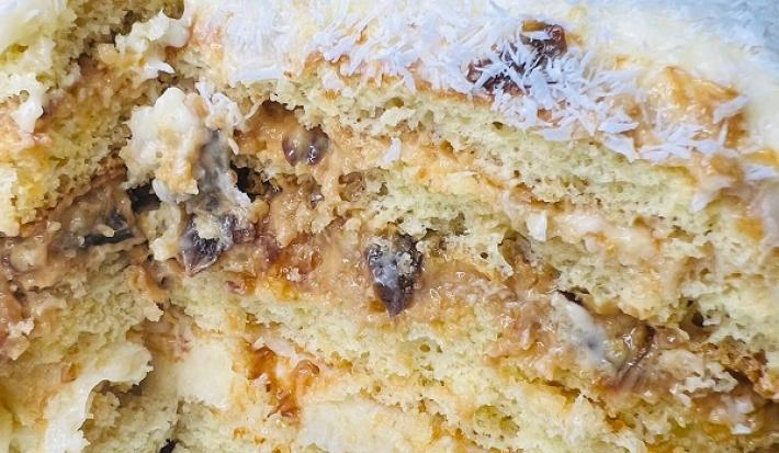 Foto da receita de Massa de Bolo de Leite Ninho. Observa-se um bolo de 3 camadas com doce de leite, ameixa e coco na cobertura.