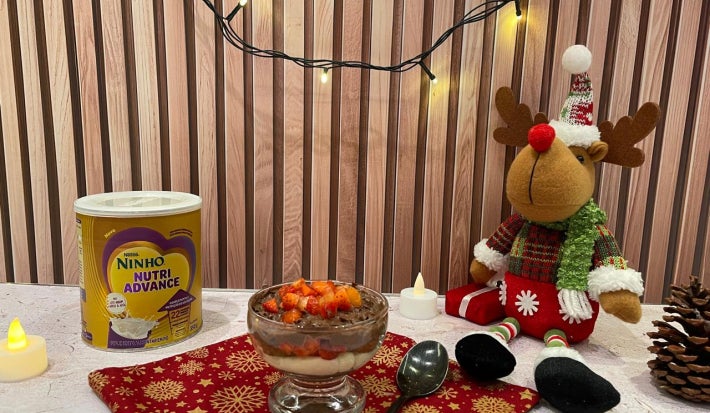 Fotografia em tons de vermelho e natal com uma taça de pavê de chocolate e morango ao centro.