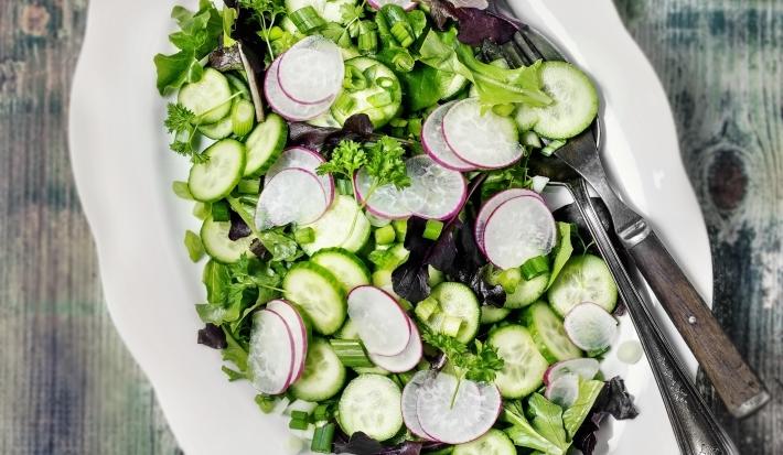 Fotografia vista de cima de um recipiente de vidro raso branco, com uma salada de acelga com cebolinha-verde com tempero, vinagre, azeite e limão.