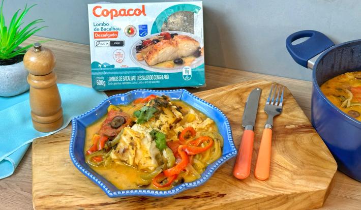 Fotografia em tons alaranjado e azul de um pranto servindo arroz e lombo de bacalhau com pimentões.