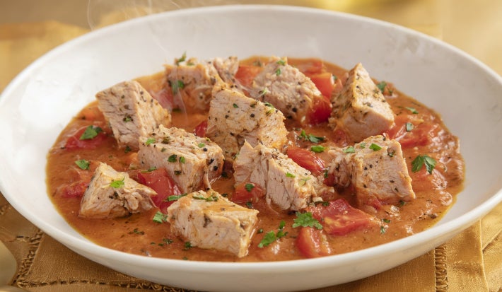 Goulash moderno de atum servido em prato fundo, com cubos de peixe em molho de tomate encorpado e ervas frescas.