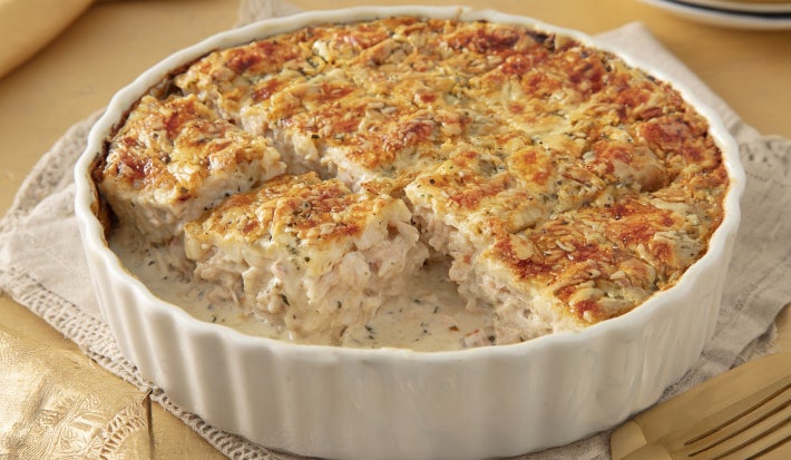 Caçarola cremosa assada com frango e molho branco, gratinada com superfície dourada, servida em refratário branco.