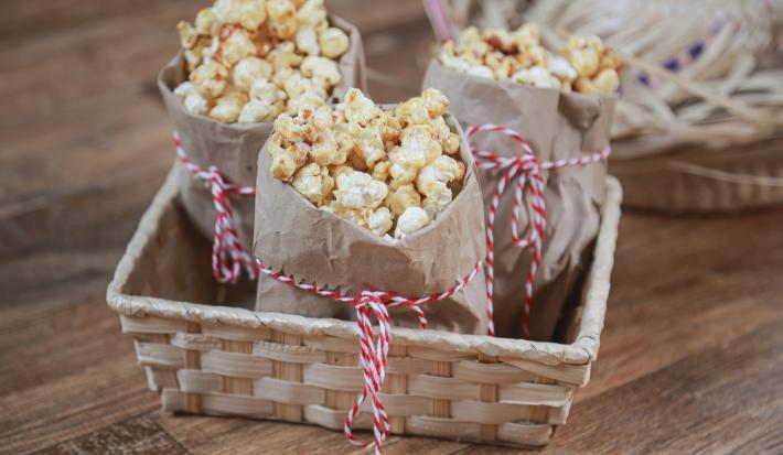 Imagem de uma cesta de palha com três saquinhos de papel com pipoca doce com Farinha Láctea Nestlé.