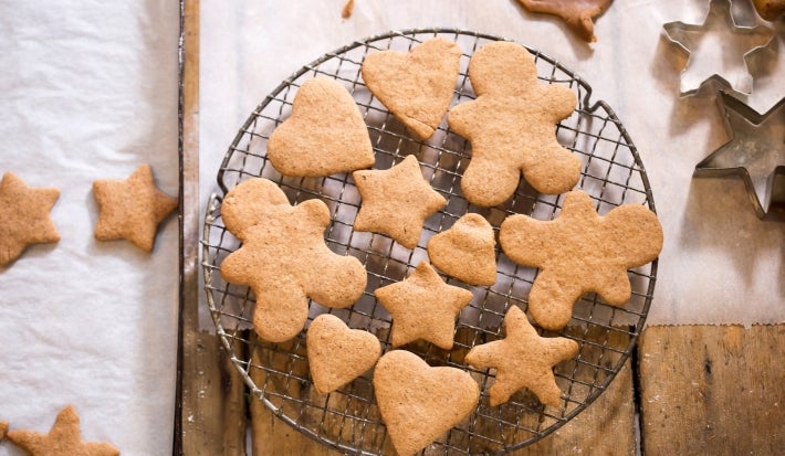Em cima de uma mesa, grade com biscoitos em formato de coração, estrelas e bonecos de gengibre.
