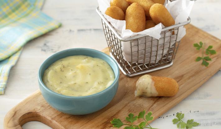 Foto da receita de Molho de Alho com Biomassa de Banana Verde. Observa-se um potinho azul com o molho e ao lado uma cestinha de bolinho de mandioca frito com papel toalha