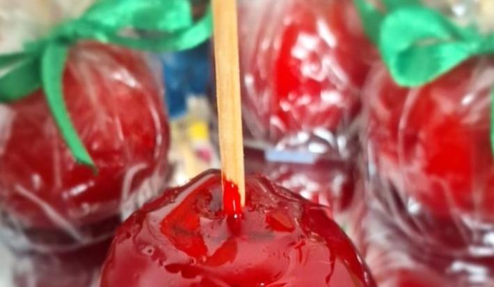 Fotografia de algumas porções de beijinho do amor. A porção da frente está com um palitinho, mas as do fundo estão dentro do saquinho fechado.