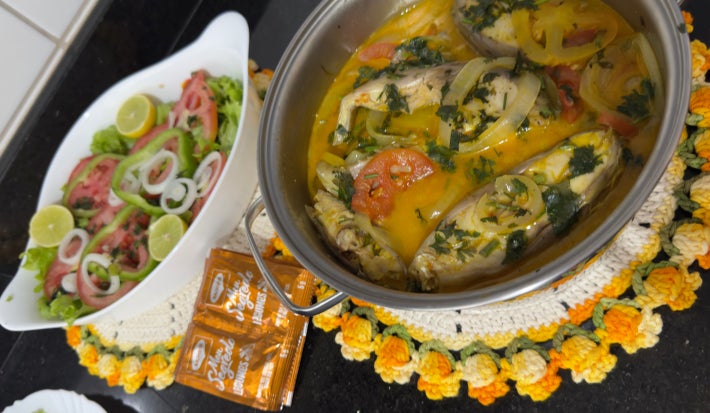 Moqueca de tilápia com tomates, cebolas e pimentões em uma travessa