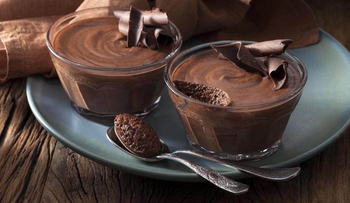 Foto de duas pequenas tigelas com mousse de chocolate dentro em cima de um prato azul