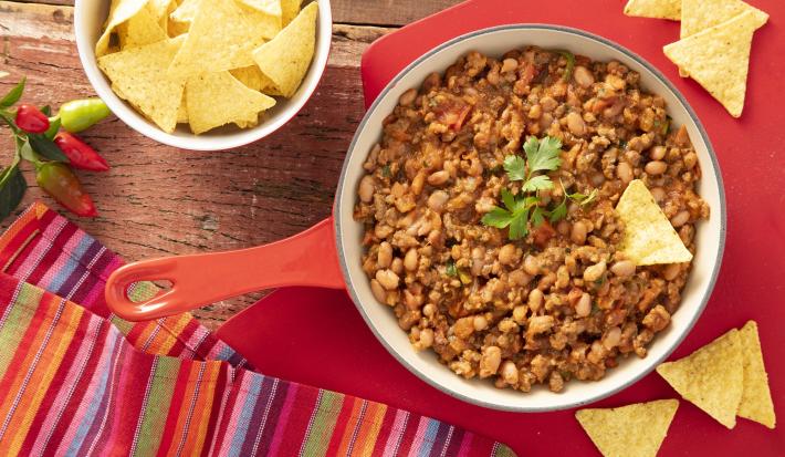 Imagem vista de cima de uma panela com o chilli e um pote de nachos.