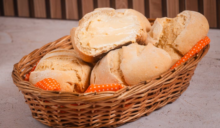 Pães de milho caseiros em cesta, um cortado com margarina Deline derretida por cima
