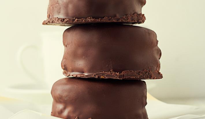 Fotografia de três pães de mel cobertos com chocolate, estão empilhados, um por cima do outro.arfo.