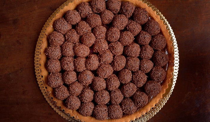 Fotografia vista de cima de uma torta com recheio de bolinhas de brigadeiro passadas no granulado.