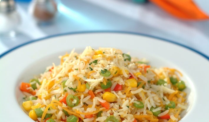 Prato de porcelana branco com porção de arroz colorido com milho, ervilha, cenoura ralada e coentro picado.