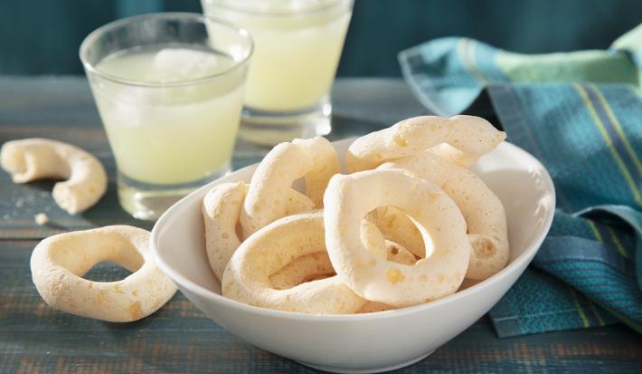 Foto da receita de Biscoito Globo. Observa-se uma tigela com os biscoitos dentro e atrás dois copos de limonada para compor a decoração da foto