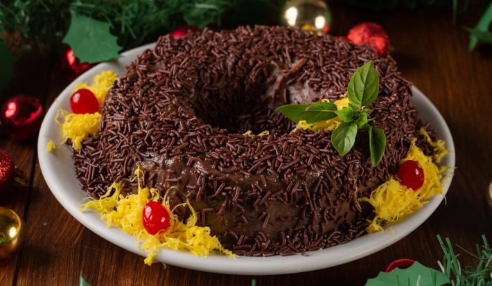 Receita de Brigadeirão de Natal, tradicional e delicioso, feito com Leite MOÇA, NESTLÉ Creme de Leite, Chocolate em Pó NESTLÉ CHOCOLATERIA, açúcar, ovos e margarina, decorado com fios de ovos, cerejas e sobre uma mesa de natal