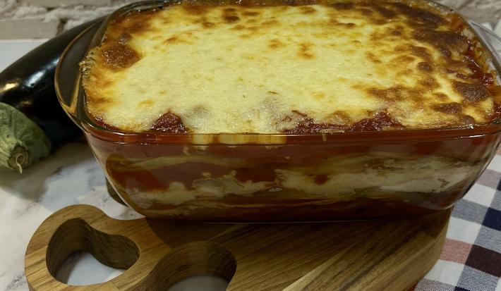 Foto da receita de Lasanha de Berinjela Maggi, servida em uma travessa de vidro retangular, sobre uma tábua pequena de madeira
