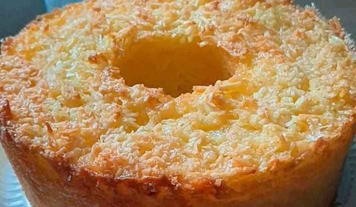 Foto da receita de Bolo Caseiro de Aipim. Observa-se um bolo com furo no meio assado e com coco por cima douradinho