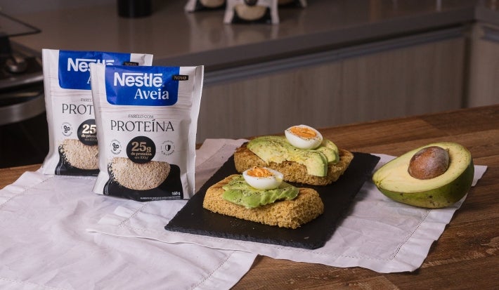 Foto da receita de toast proteico servida em duas porções sobre uma pedra preta em cima de uma mesa de madeira com metade de um avocado ao lado