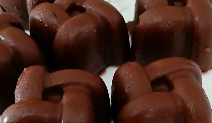 Fotografia de seis unidades de bombons recheados com banana e açaí, os quais estão sobre um prato branco.