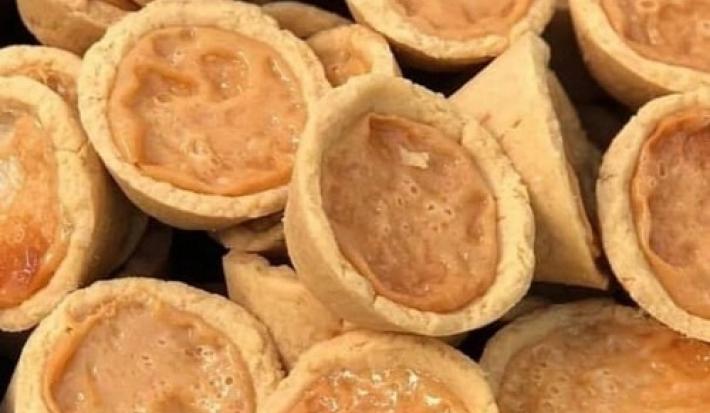Foto em tons de bege e marrom claro da receita de empadinha de leite moça servida em diversas porções dispostas aleatoriamente uma sobre as outras