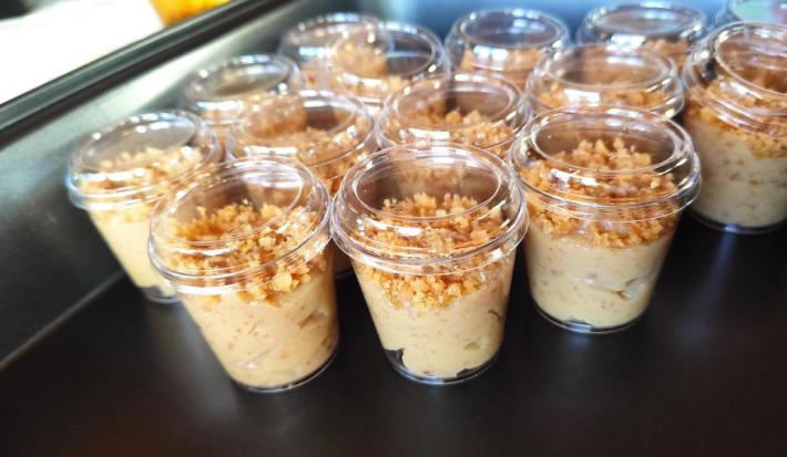 Foto da receita de brigadeiro de paçoca de colher servida em diversas porções em copinhos plásticos sobre uma base prateada