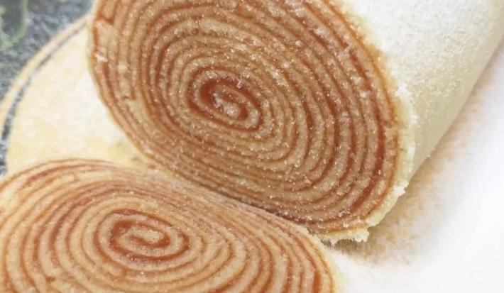 Foto da receita de Bolo de Rolo da Josirane Mikelle. Observa-se um bolo de rolo cortado sobre um prato decorado.