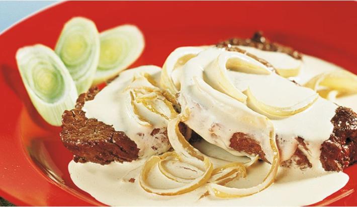 foto tirada de uma prato redondo e vermelho com dois bifes, creme por cima e cebolas