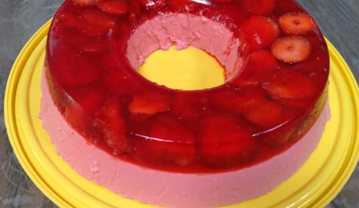 Foto em tons de vermelho da receita de super gelatina de morango servida sobre uma base circular amarela