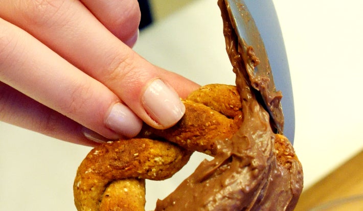rosquinha fit de banana e aveia com cobertura de Nutren chocolate sendo espalhada