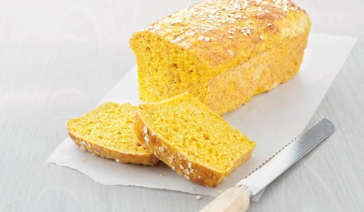 fotografia em tons de branco e amarelo tirada de um pão e duas fatias do mesmo e ao lado uma faca.