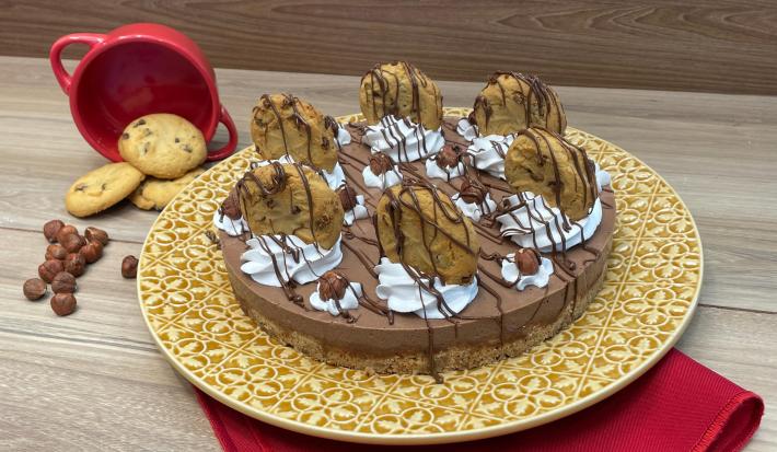 Fotografia mostra uma cheesecake de chocolate decorada com chantilly e cookies cobertos com chocolate.