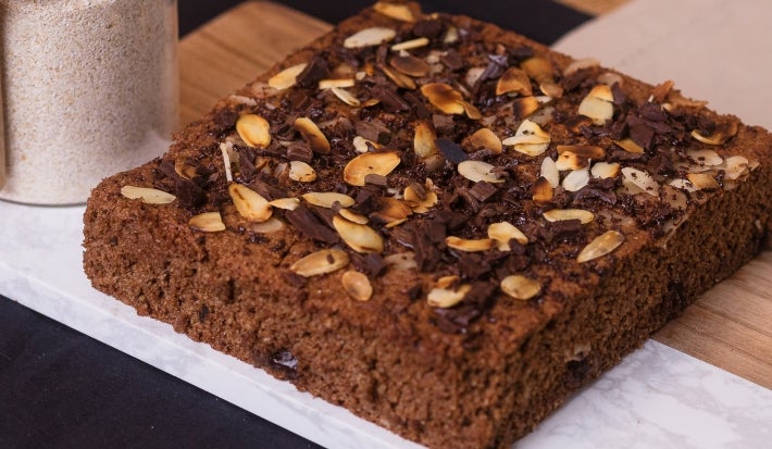 Receita de bolo proteico molhadinho servida em um porção grande sobre uma mesa de madeira