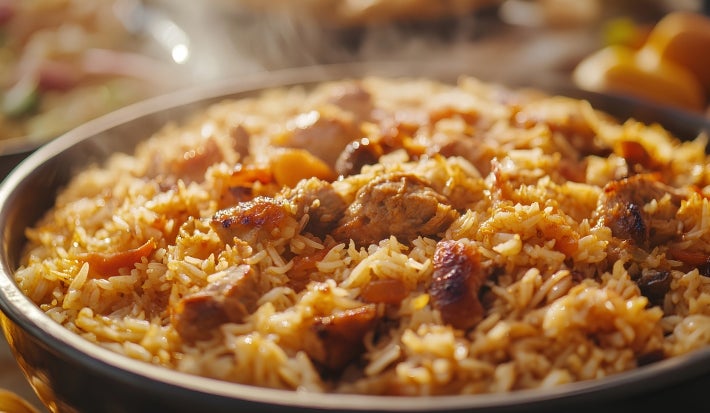 Um prato de Arroz Natal é apresentado em um prato redondo, repleto de arroz soltinho e colorido. O arroz é misturado com pedaços suculentos de peito de frango.
