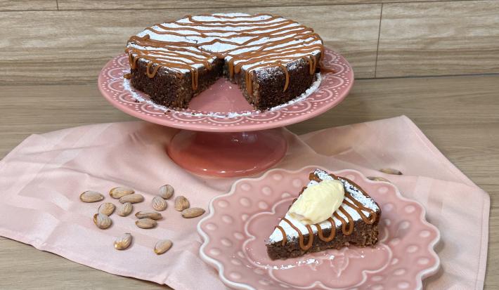 Fotografia em tons de rosa com uma toalha e um prato bailarina ao centro. Em cima do prato existe uma receita de torta italiana com recheio de chocolate e caramelo toffee