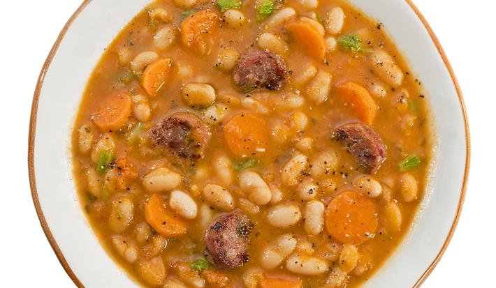 fotografia em tons de branco e laranja tirada de um prato redondo visto de cima dentro contém sopa