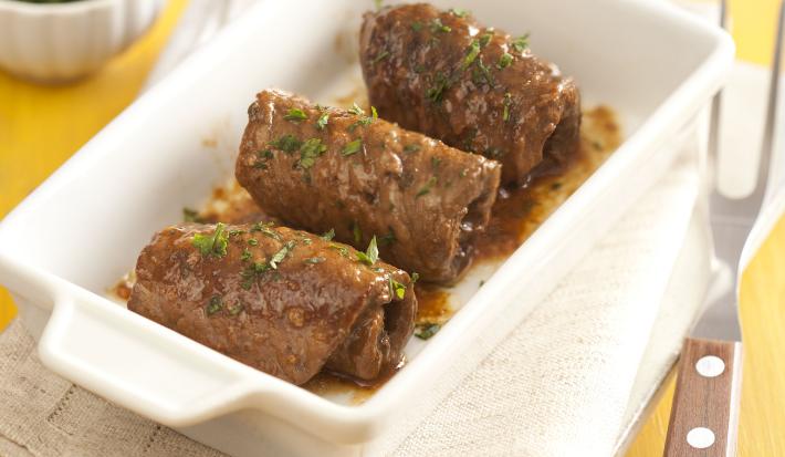 em uma mesa amarela. contém panos brancos e acima um recipiente que comporta os enrolados de carne.