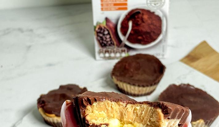 Foto da receita de bombom de cacau com banana servida em diversas porções sobre uma mesa de mármore branca com uma embalagem de nature's heart cacau em pó ao fundo