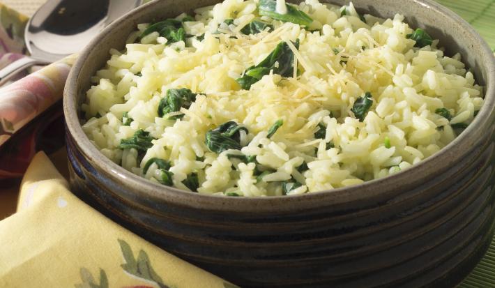 fotografia em tons verde e marrom. Um recipiente comporta o arroz e ao lado um pano na cor amarelo com rosas.