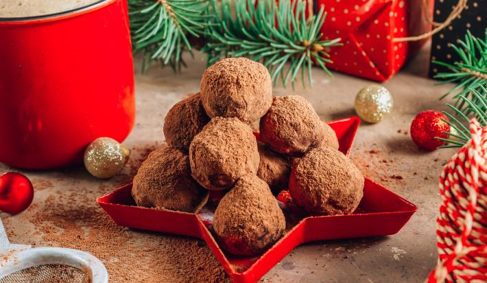Fotografia mostra uma bandeja vermelha com trufas de chocolate perfeitas, cobertas com uma camada de chocolate em pó aveludado.