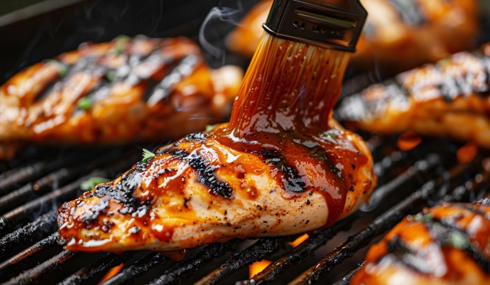 Fotografia de um peito de frango feito na churrasqueira com molho barbecue