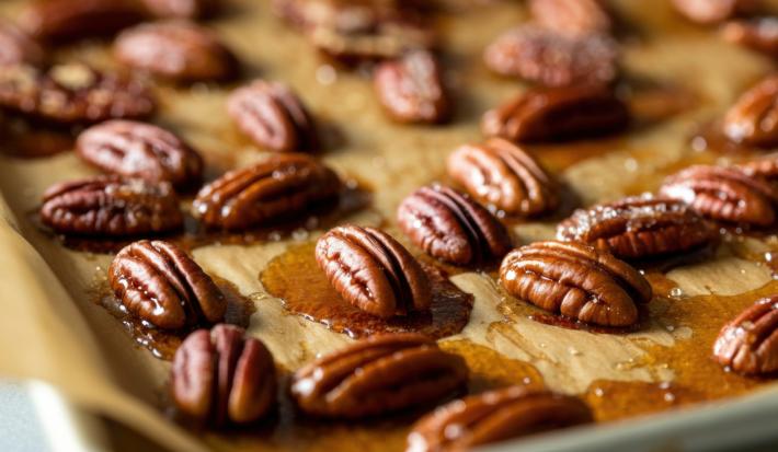Fotografia de castanhas caramelizadas sobre uma forma com papel manteiga.