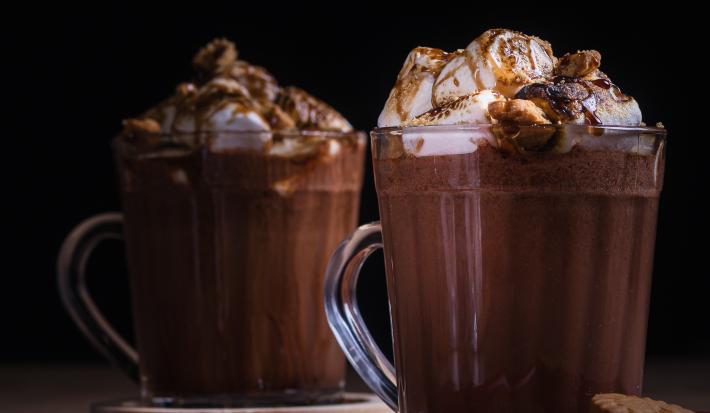 Receita de smorecaccino servida em duas canecas de vidro sobre uma mesa de madeira