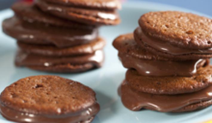 fotografia em tons de marrom, branco e azul tirada de uma bailarina branca com Whoopies Nescau por cima com recheio de brigadeiro